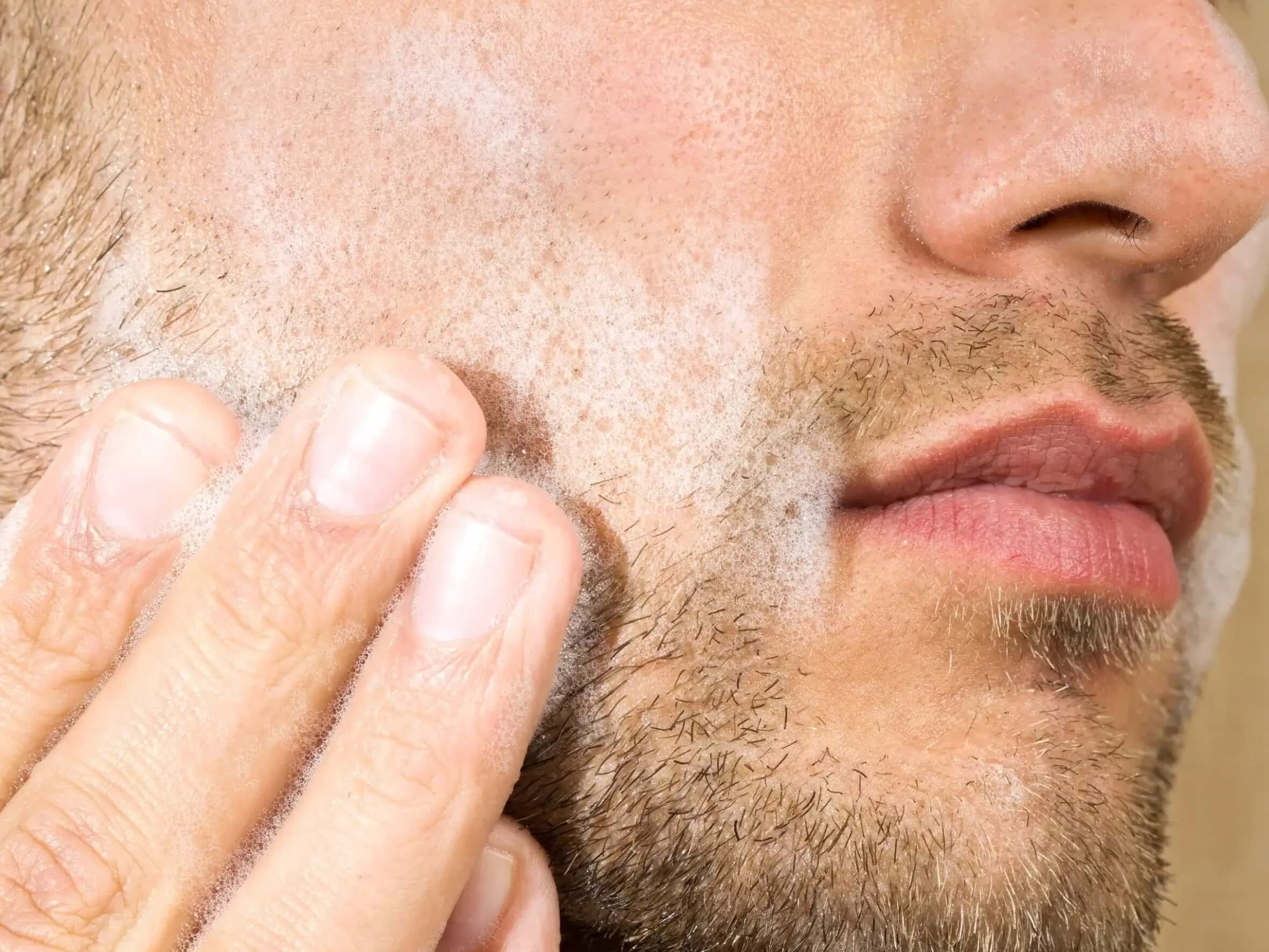 Close-up of a man applying cream to his face