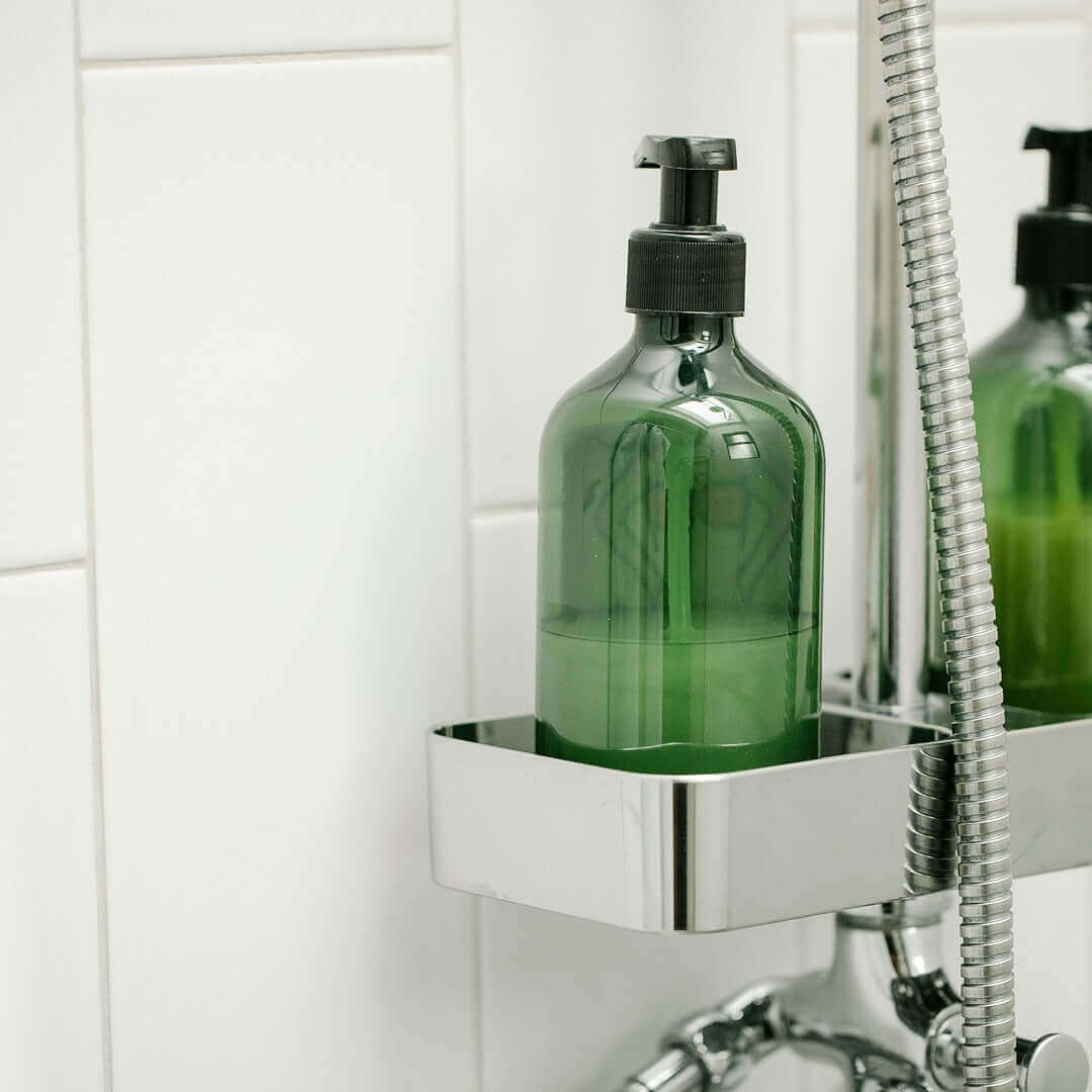 Green soap dispenser on a metal shelf in a bathroom setting