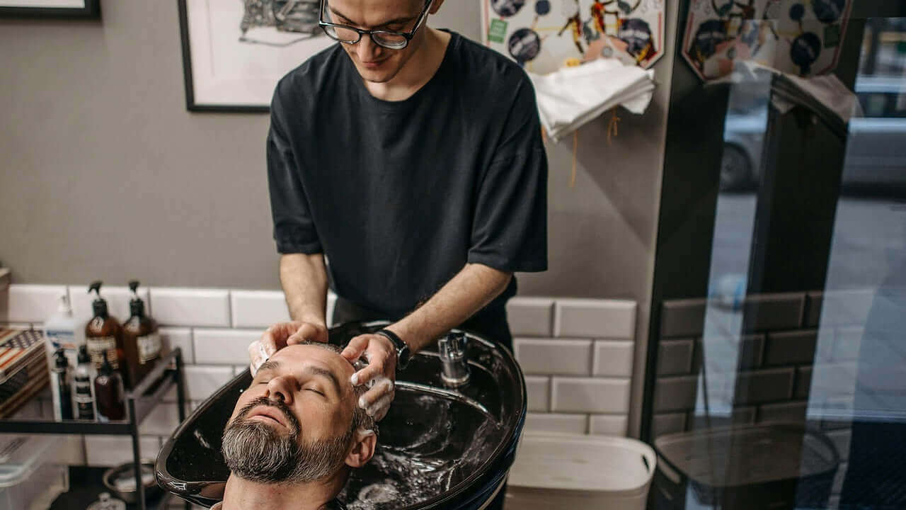 Man shampooing another man at a barbershop
