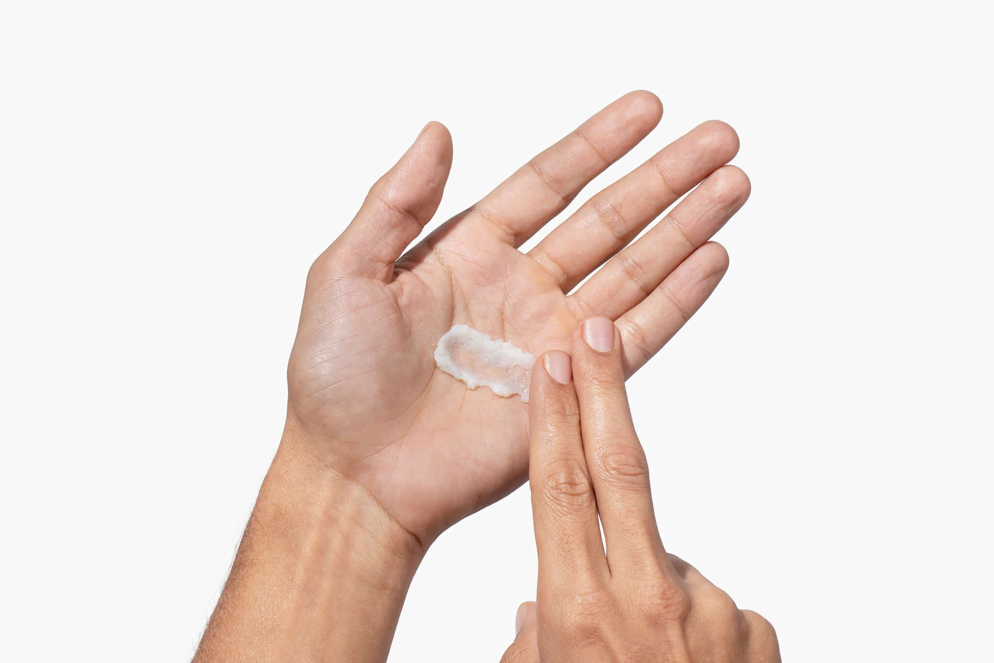 Hand applying a small amount of beard balm to another hand on a white background